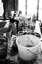 Black and white photo of a cozy art studio with drawing tools and sketches on a wooden table.