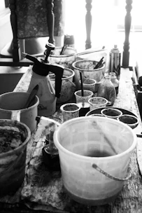 Black and white photo of a cozy art studio with drawing tools and sketches on a wooden table.