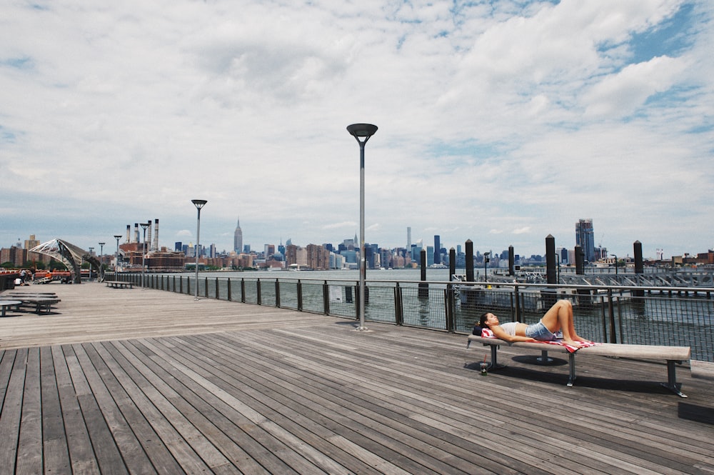 a woman laying on a bench on a pier