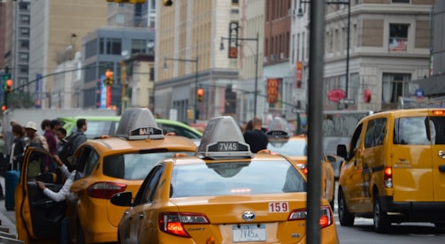 A busy street scene with taxis picking up passengers.