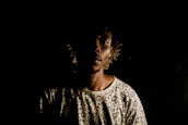 An artistic shot of a model wearing a theatrical, conceptual outfit under moody lighting.