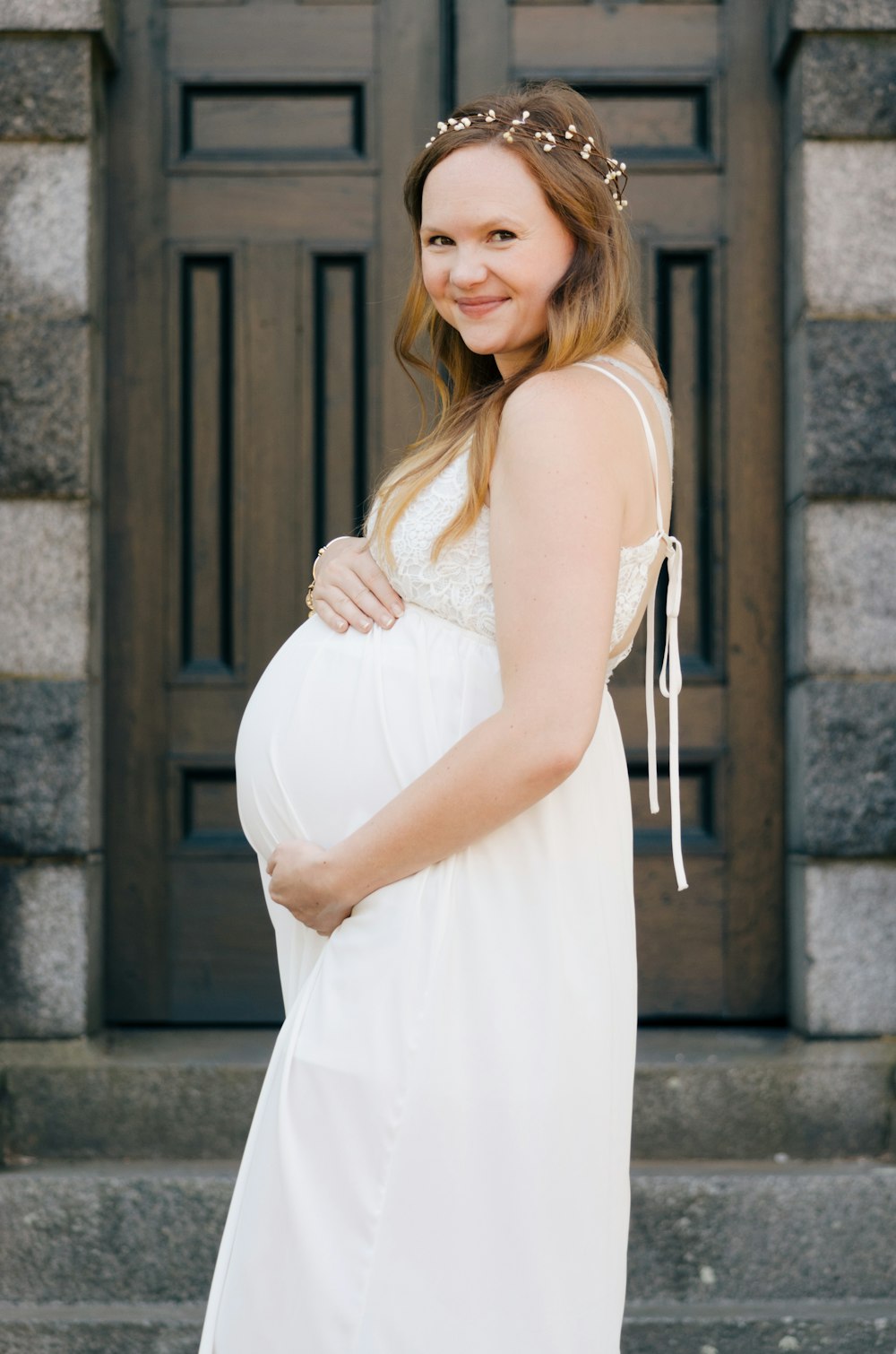 木製のドアのそばに立つ妊婦