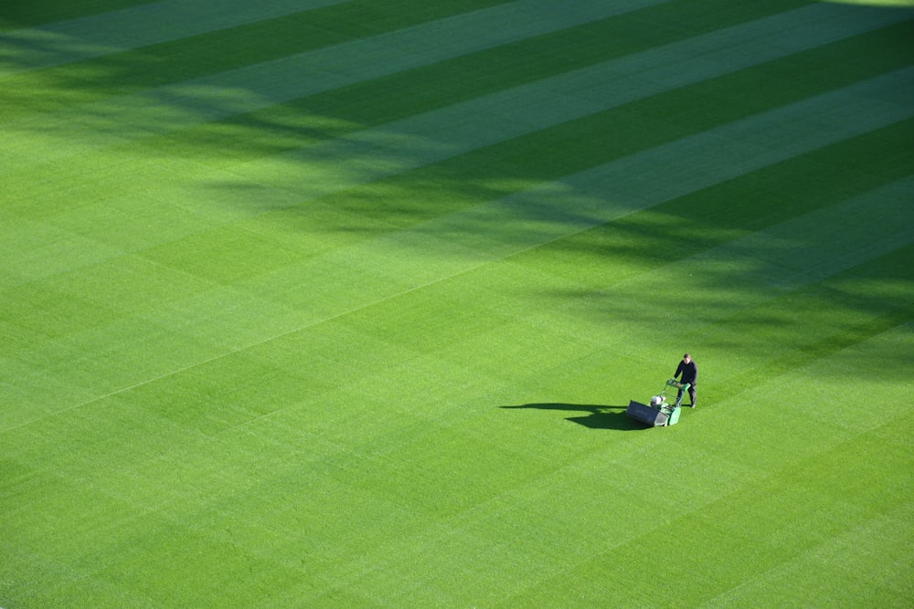 Fotografía aérea de una persona recortando el campo deportivo durante el día