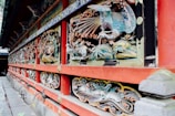 Intricate and colorful carvings adorn a traditional Japanese building, featuring detailed depictions of animals and nature motifs. The designs are crafted into the wooden structure, highlighted by vibrant shades and are framed by bold red painted beams.