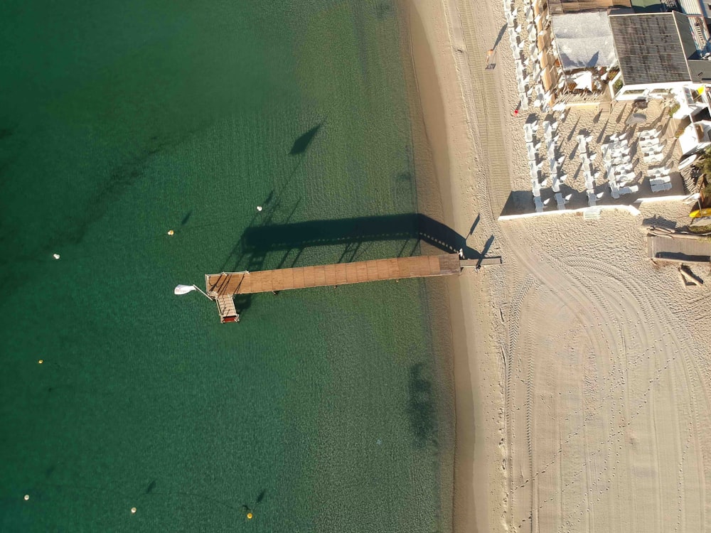 foto aérea da costa e doca de madeira marrom em direção ao mar durante o dia