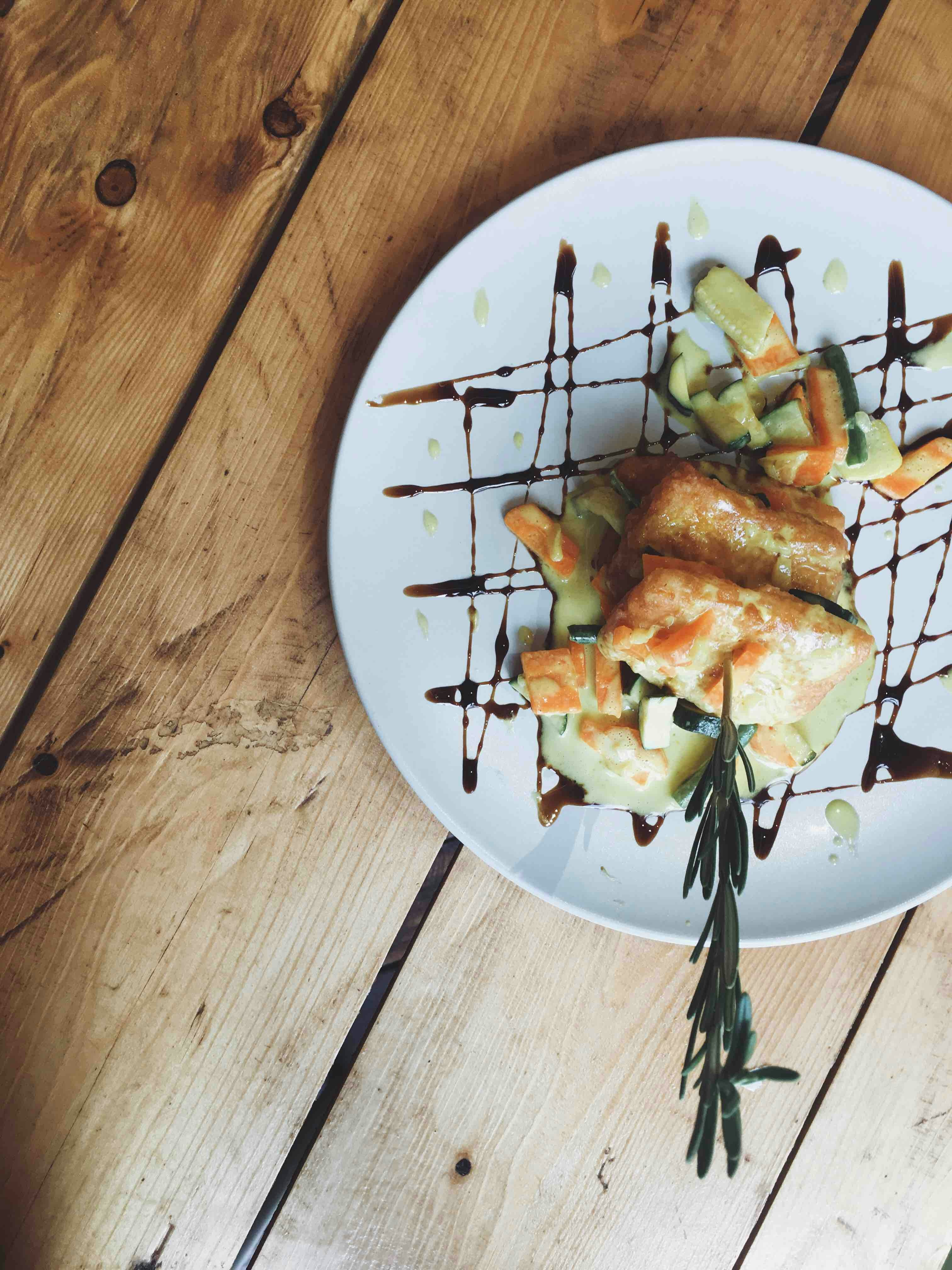 Dark balsamic reduction drizzling from a small pitcher over a white plate, Italian kitchen setting