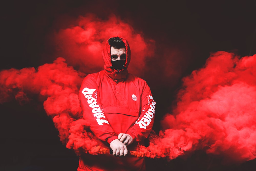 hombre con chaqueta roja con capucha Thrasher con humo rojo