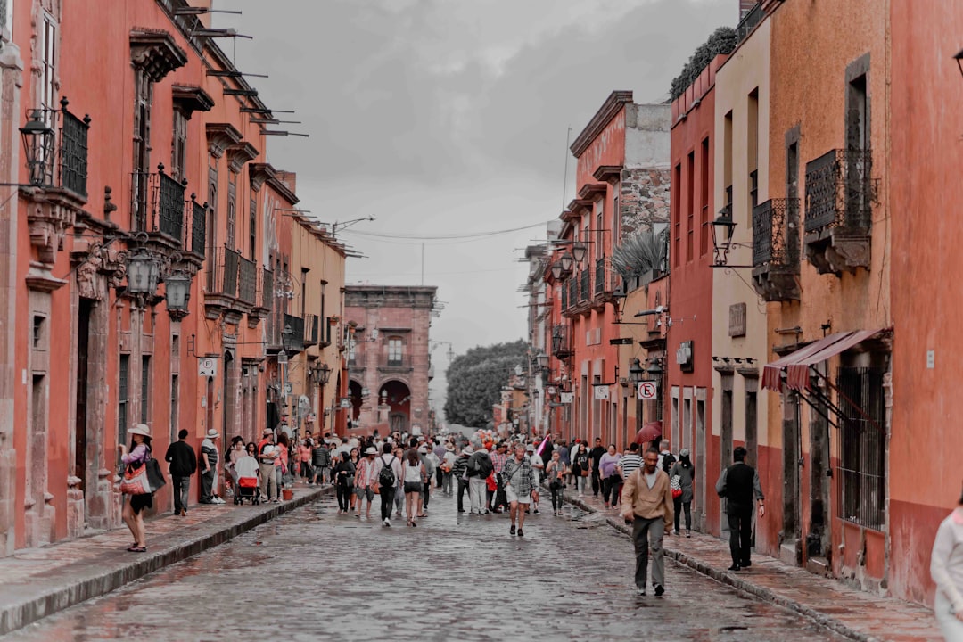 people walking between orange concrete buildings,