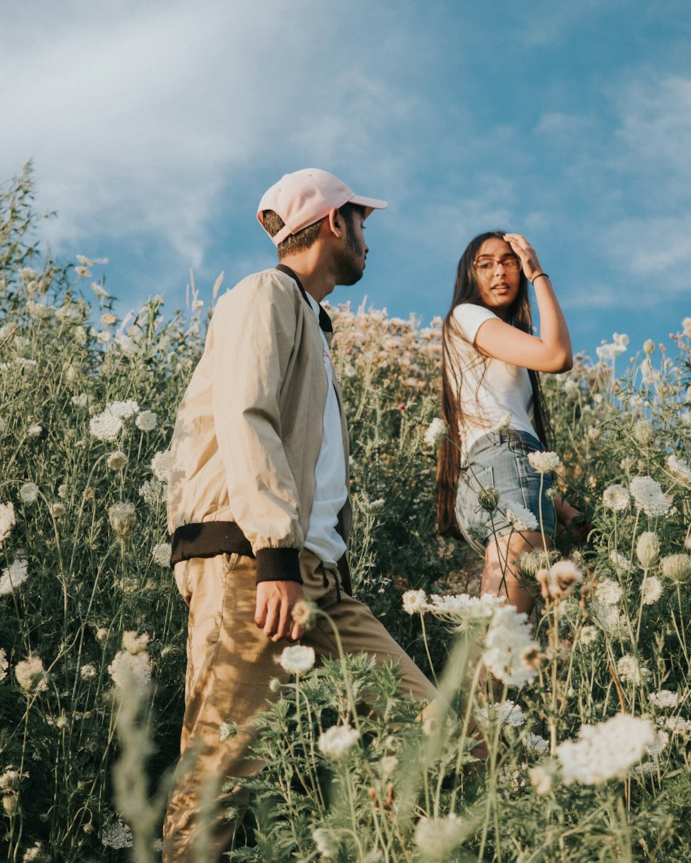 man and woman climbing white wild carrot flower fields