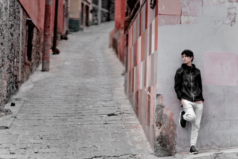 man leaning on gray wall