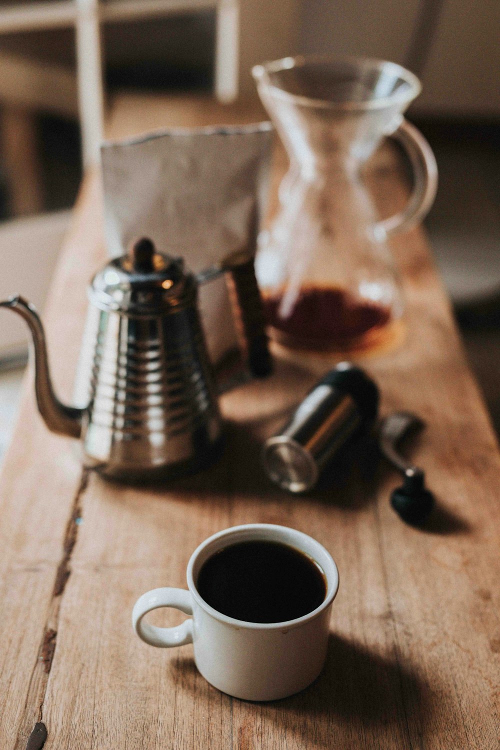 Fotografia de foco raso de caneca de café branco com café preto na mesa