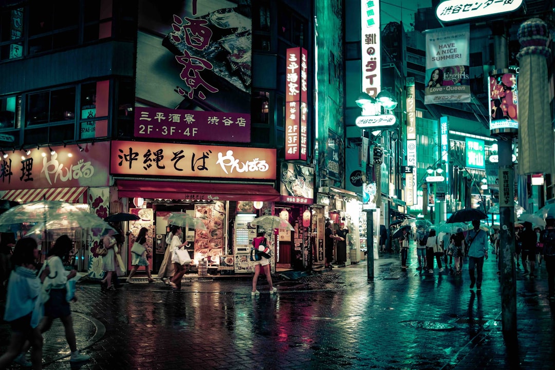 people walking near buildings at night, Umbrellas in a busy street