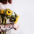 woman holding yellow sunflowers on her right arm