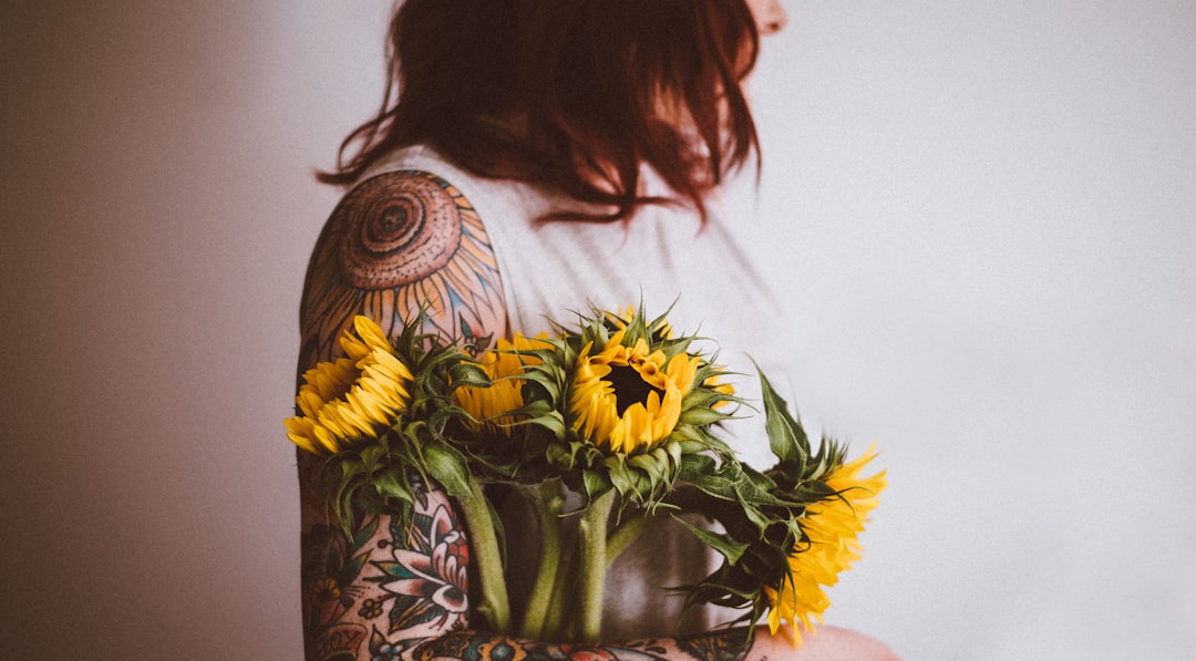 Tattooed woman holding sunflowers