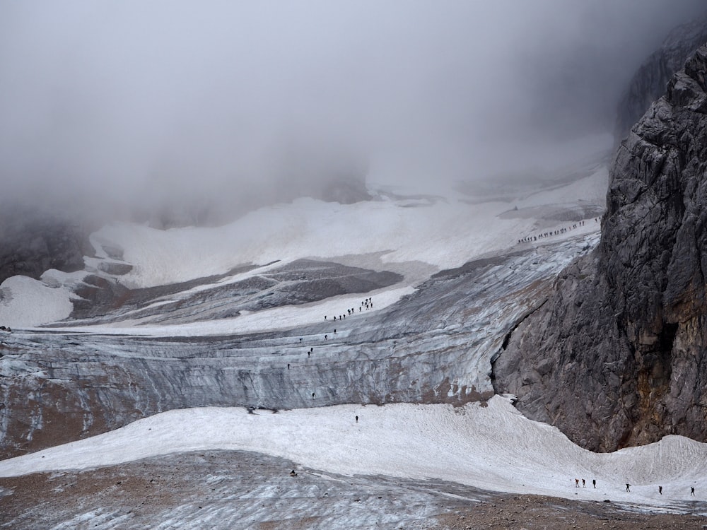 group of people walking on mountain trail under sea of clouds