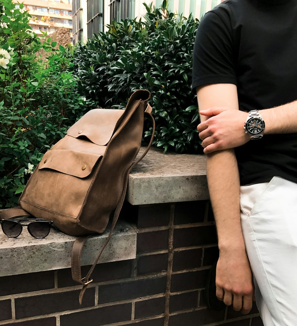 Tasche auf der Oberfläche in der Nähe der Sonnenbrille mit Pflanzen auf der Rückseite