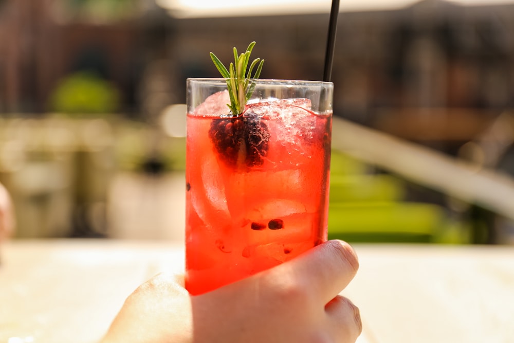 Person, die ein Glas Getränk in der Hand hält