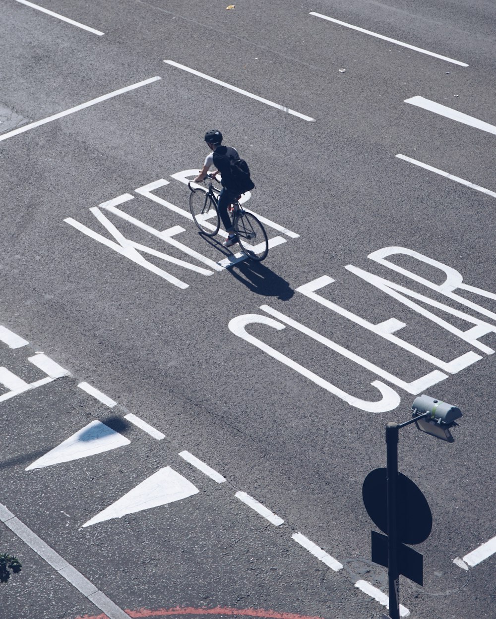 Mann in roter Jacke fährt Fahrrad auf grauer Asphaltstraße