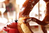 Hand-drawn illustration of a pretzel and flames in rustic red tones.