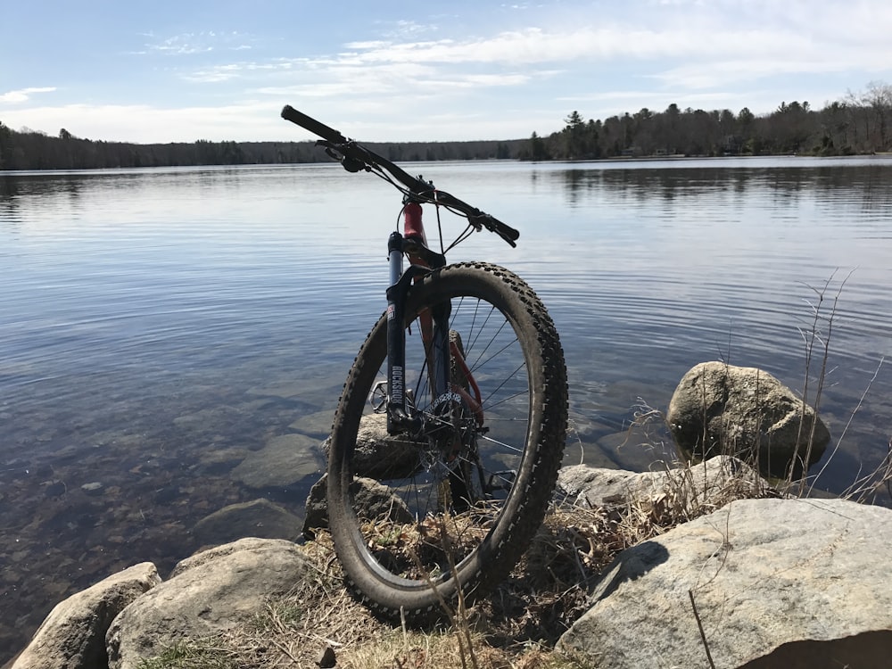 black mountain bike on gray stones near water at daytime