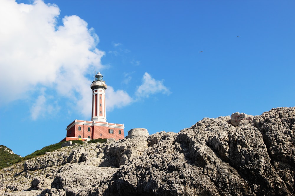 brown and white concrete lighthouse on rock formation during daytime