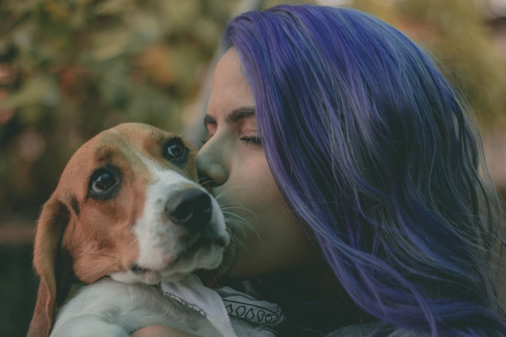 Mujer besando perro marrón y blanco