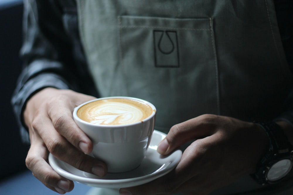 person holding white ceramic cup