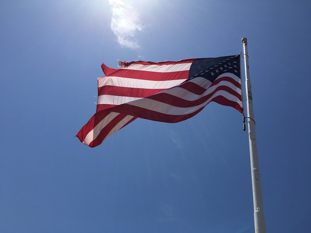 photographie en contre-plongée du drapeau américain sous un ciel bleu clair