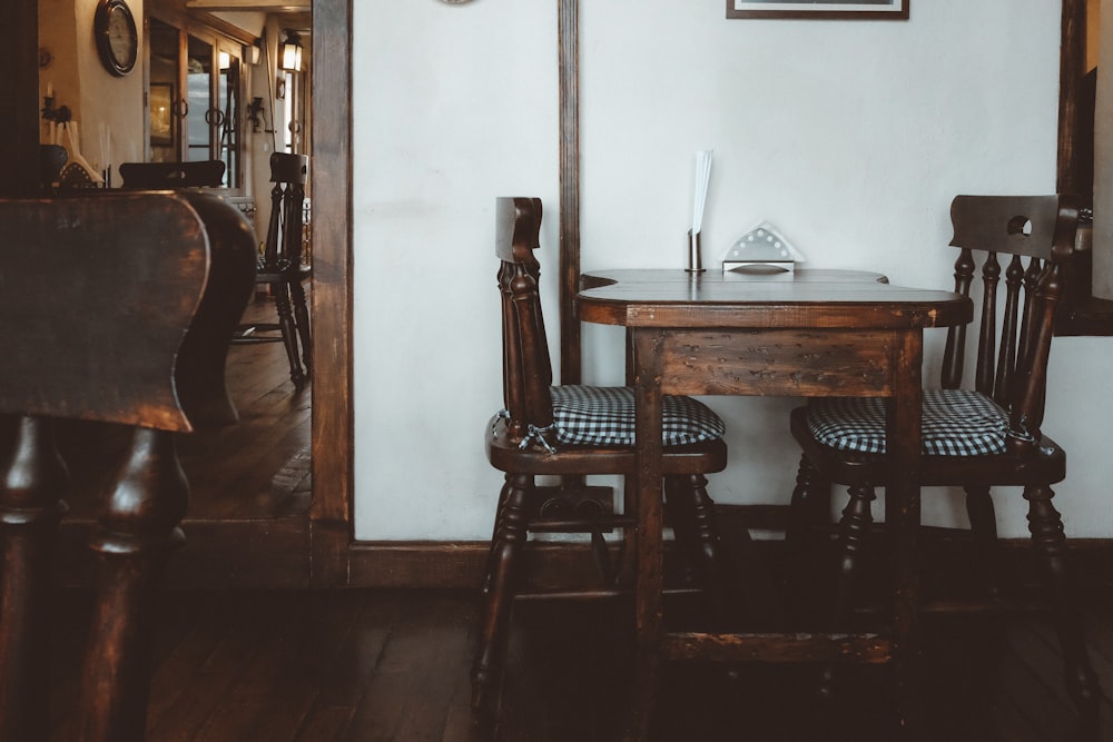 brown wooden 3-piece bistro set near white wall inside room