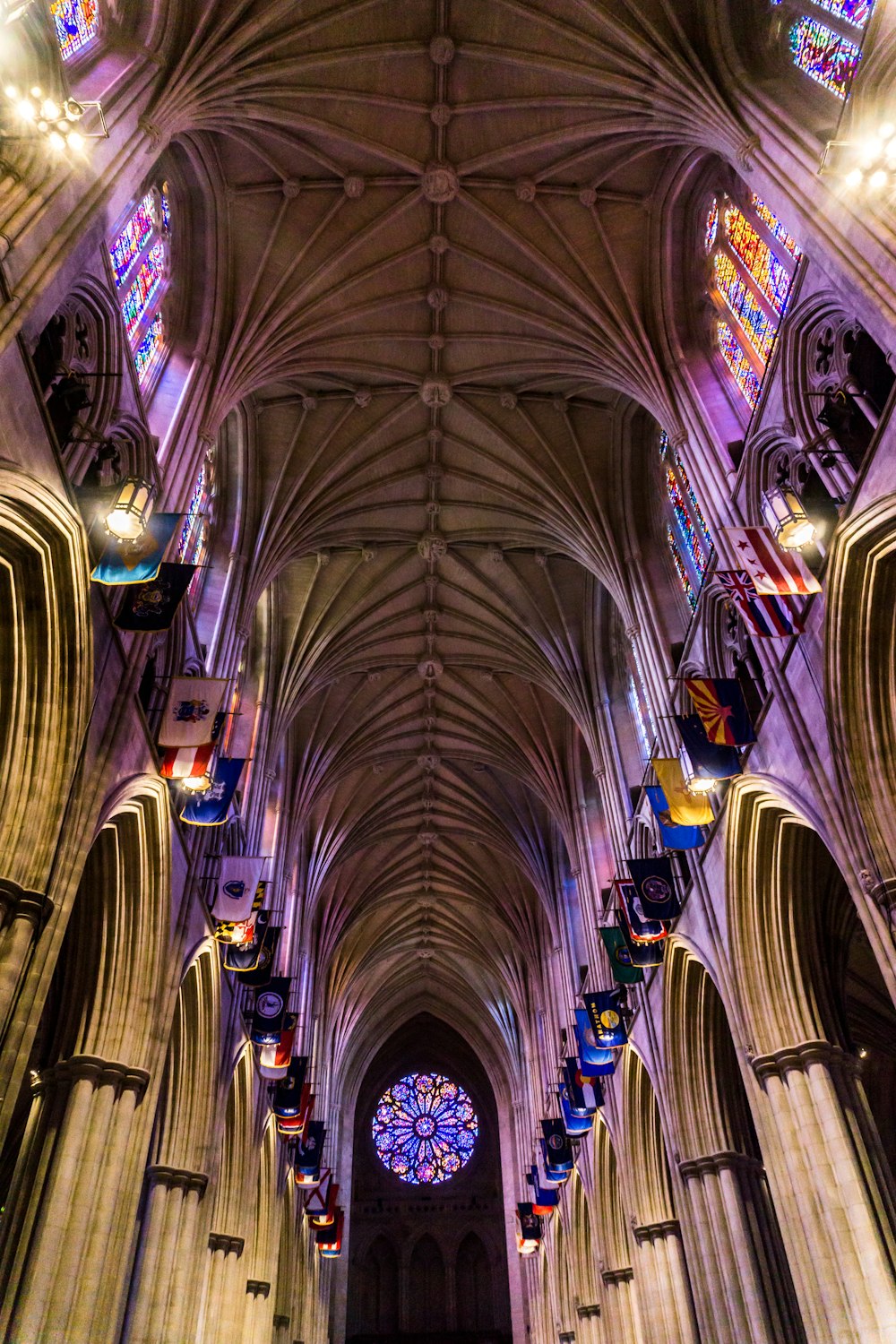 Photographie d’intérieur en contre-plongée de la cathédrale avec des vitraux multicolores