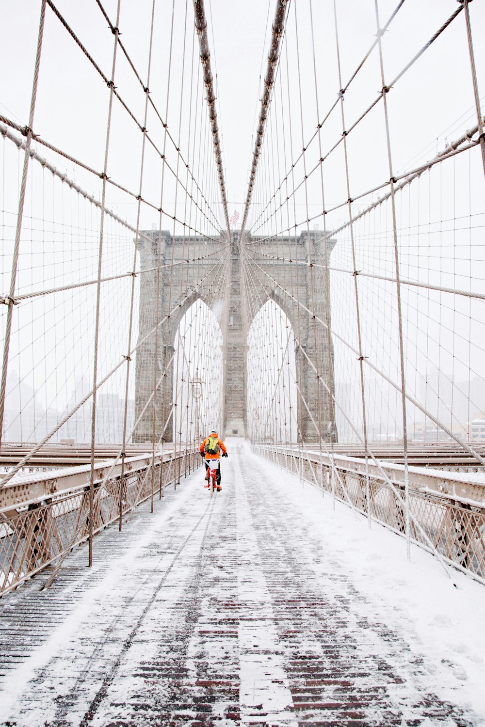 Persona en bicicleta roja corriendo en puente marrón cubierto por nieve