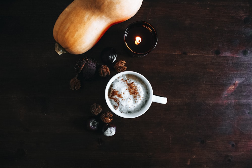 taza de café cerca de una verdura naranja sobre una superficie de madera marrón