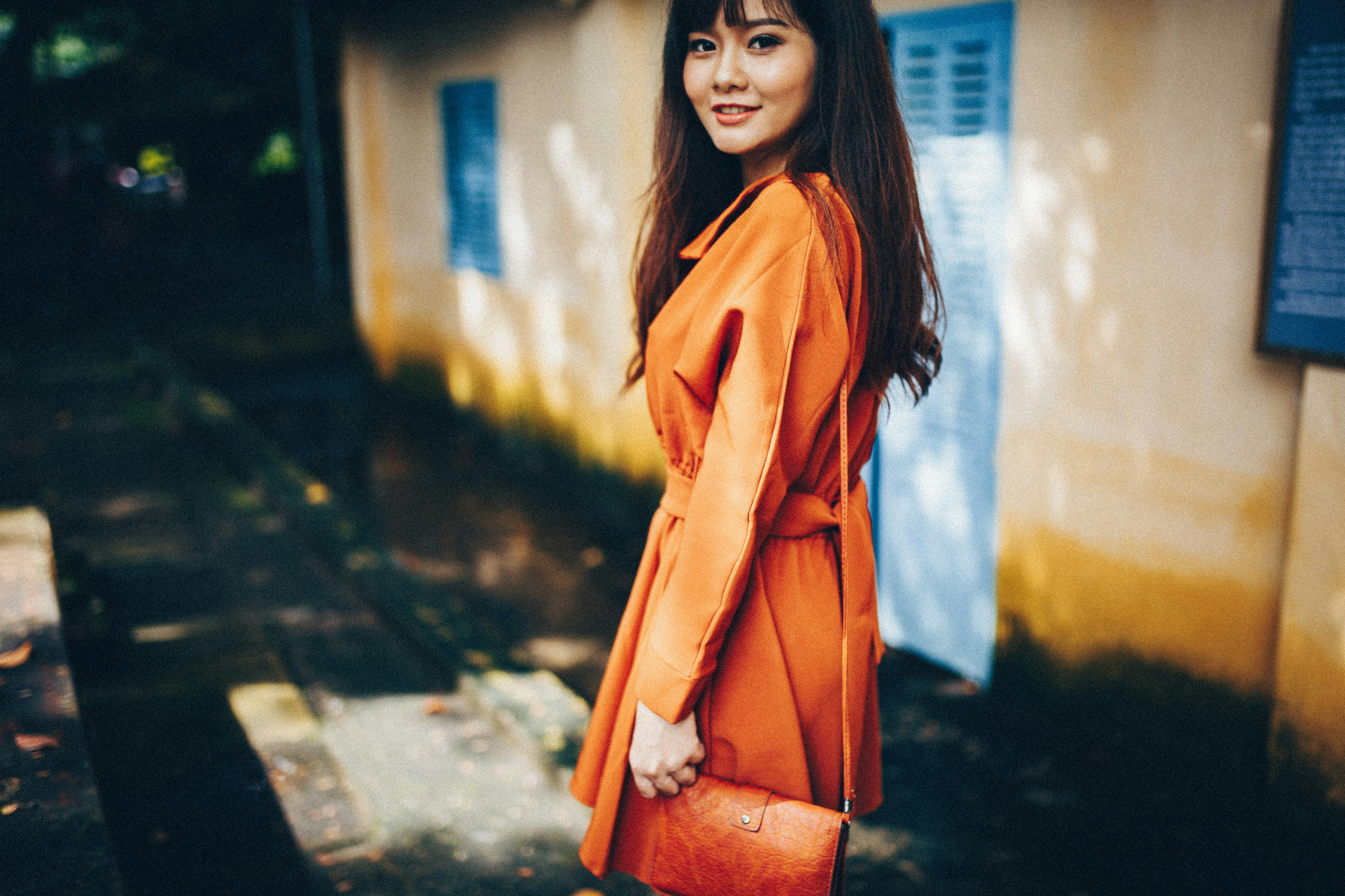 Woman in orange coat by house