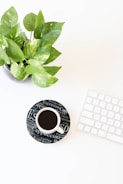 black liquid in white ceramic cup beside keyboard