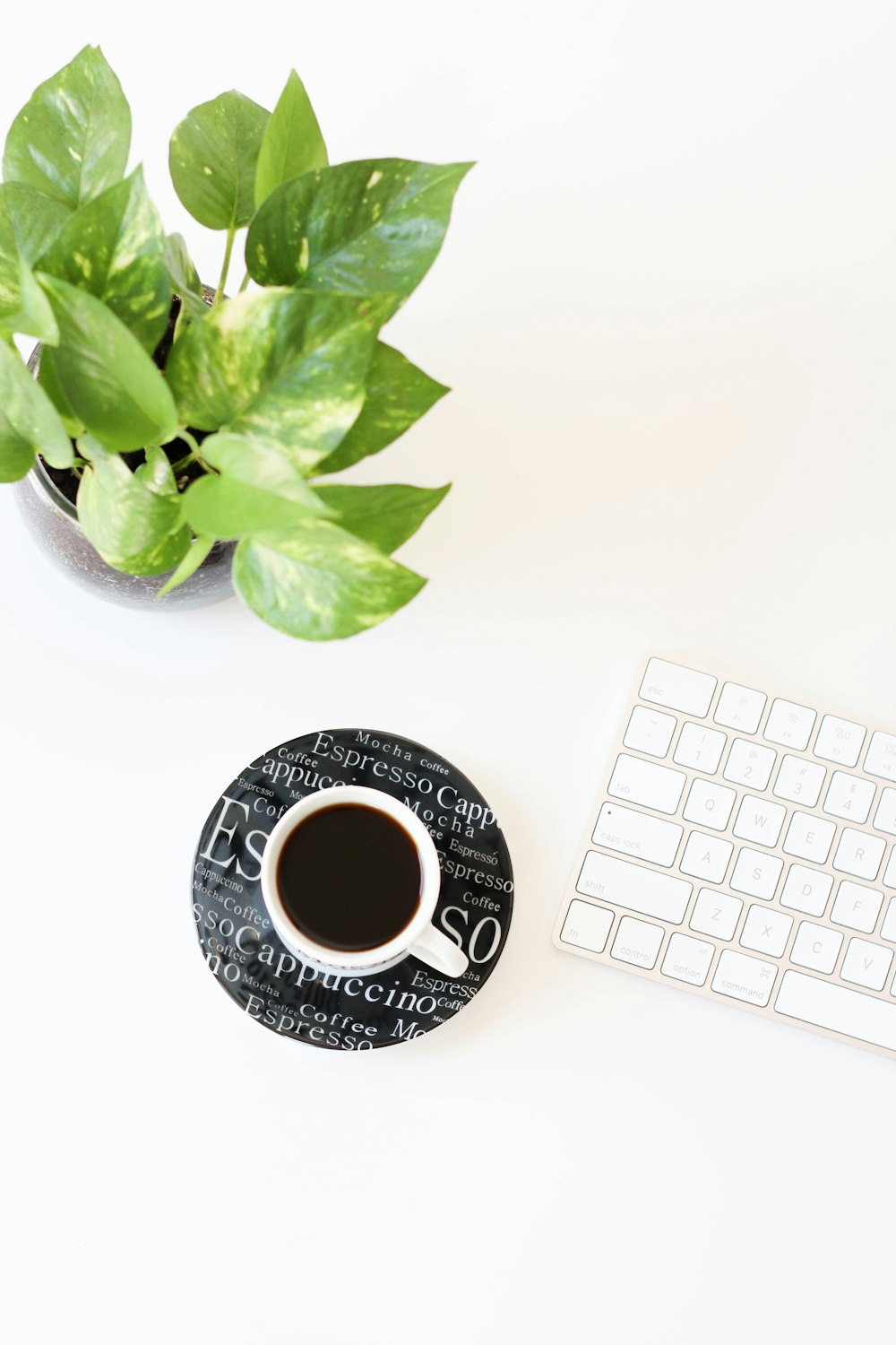 líquido negro en taza de cerámica blanca al lado del teclado