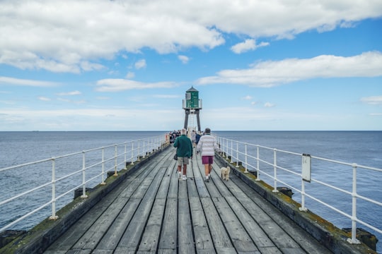 person walking on wooden dock during faytime in Whitby United Kingdom
