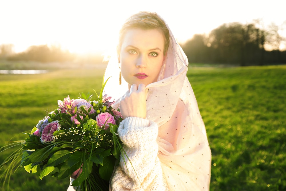 femme portant un voile rose tenant un bouquet de fleurs roses