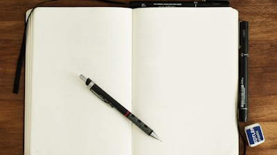 black and silver retractable pen on blank book