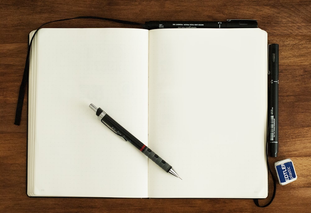 caneta retrátil preta e prateada no livro em branco