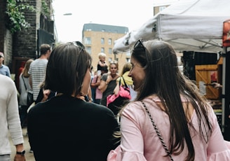 two women walking near food stalls