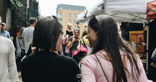 two women walking near food stalls