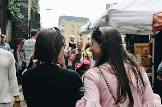 two women walking near food stalls