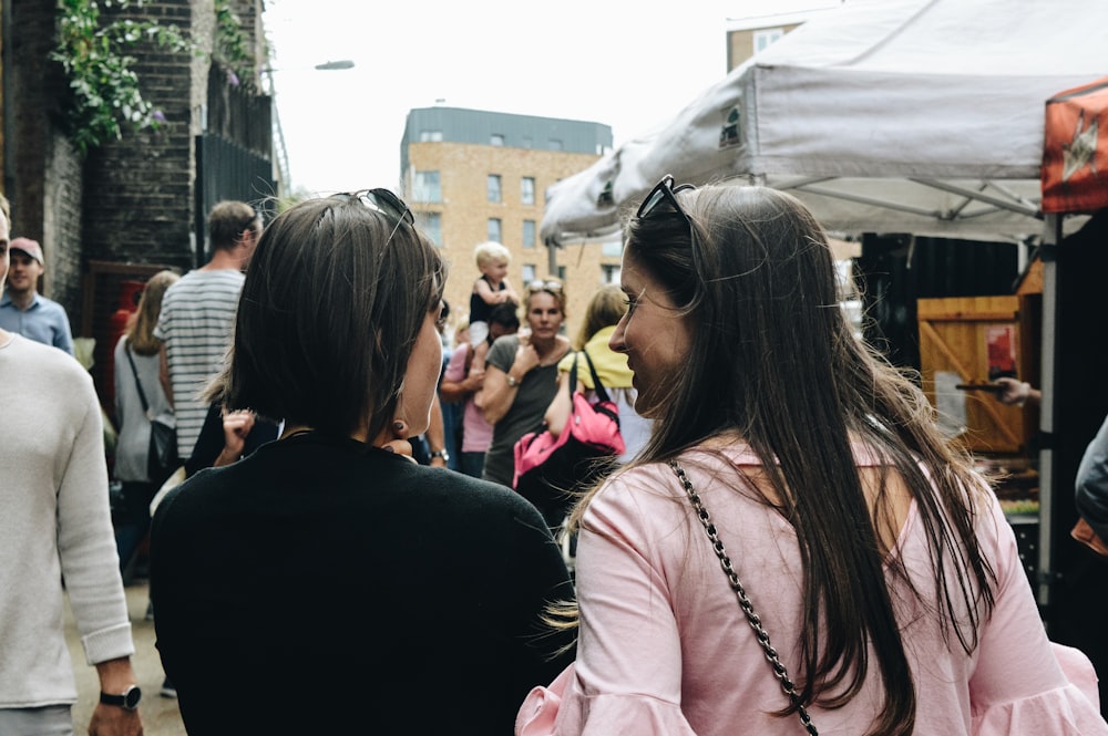 two women walking near food stalls