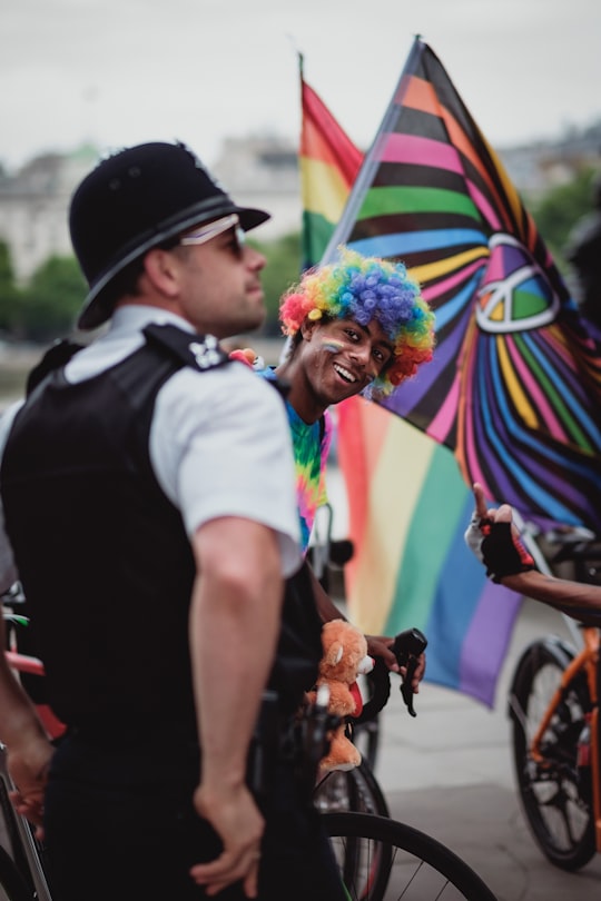 person wearing rainbow wig riding bicycle in South Bank United Kingdom