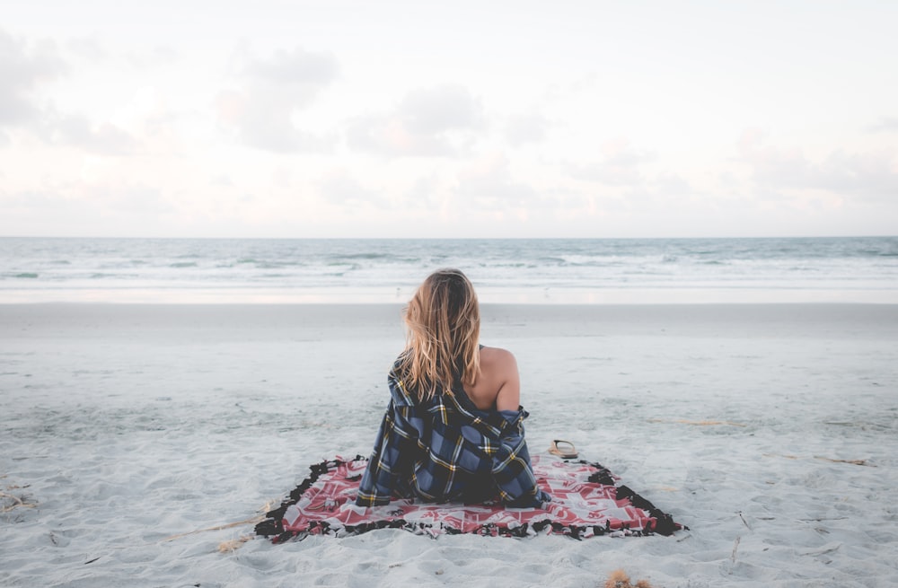 woman sitting on blanket located on shoreline