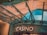 The image displays the entrance to a casino, characterized by detailed and ornate architectural elements with green metal structures and a sign that reads 'CASINO'. The background includes a glass dome and a peach-colored wall.
