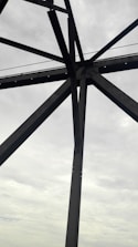 Construction workers fitting steel beams on a new bridge under cloudy sky.