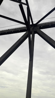 Steel beams being precisely welded on a construction site under a cloudy sky.