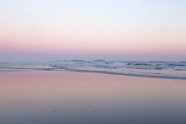 A serene beach at sunset with turquoise waters and soft waves