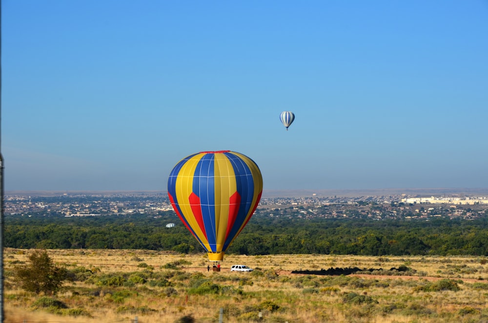 ベージュ色の大地の上空を飛ぶ2つの熱気球